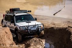 a white four wheel drive vehicle driving through mud