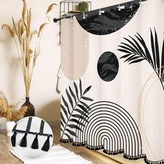 a shower curtain with black and white designs on it, next to a round mirror