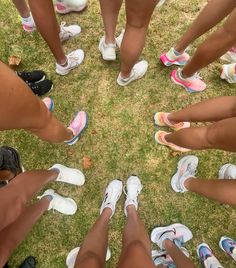 a group of people standing in a circle on top of grass with their feet together