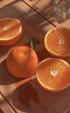 four oranges sitting on top of a wooden table