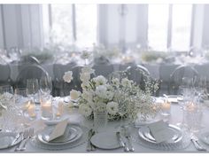 the table is set with white flowers and silverware