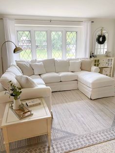 a living room with white furniture and large windows