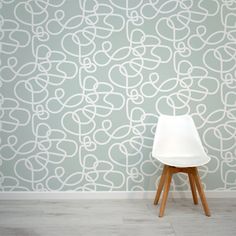 a white chair sitting in front of a wall with a pattern on it's side