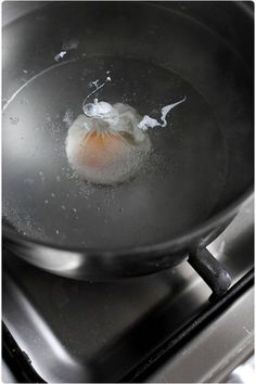 an egg is being cooked in a pan on the stove top with water and oil