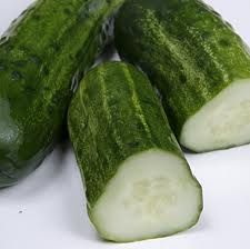 three cucumbers are sitting together on a white counter top and one is cut in half