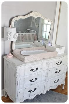 a white dresser with a baby crib and mirror