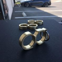 three brass rings sitting on top of a black table next to a blue car in the background