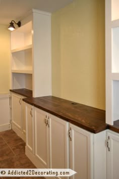 an empty kitchen with white cabinets and wood counter tops