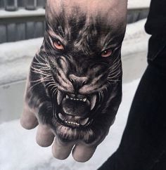 a person's hand with a black and white tiger tattoo on it, while the other hand has an orange eye