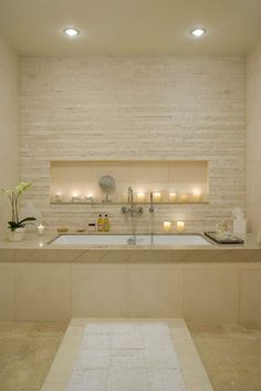 a bath room with a large tub and candles on the wall next to each other