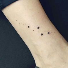 a small star tattoo on the ankle is shown in black and grey colors, with tiny stars all over it