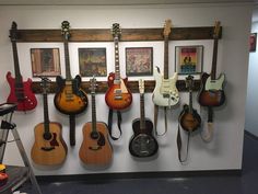 several guitars are hanging on the wall in a music studio, and there is also a guitar rack