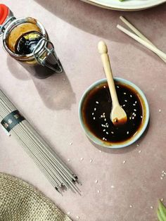 a table topped with plates and utensils filled with sauces next to chopsticks