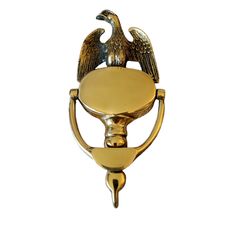 an eagle is sitting on top of a golden hook with a ball in the middle