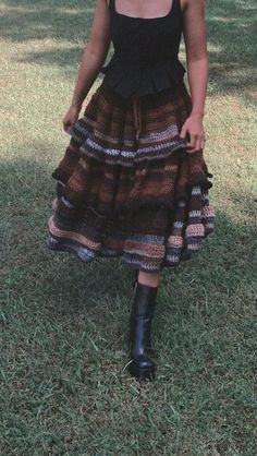 a woman standing in the grass wearing a dress and black boots with her hands on her hips