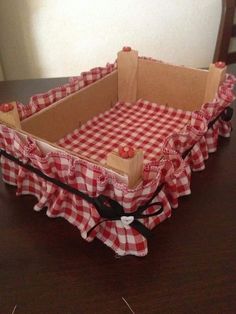 an empty box with red and white gingham fabric on the inside sitting on a table