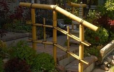 a wooden railing made out of bamboo sticks in the middle of some plants and flowers