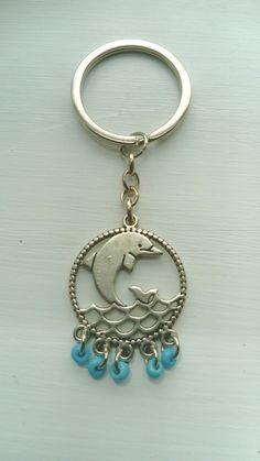 a metal keychain with a dolphin on it's face and blue beads