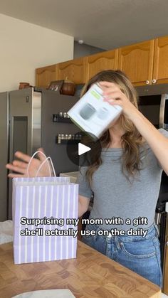 a woman is opening a gift bag in the kitchen