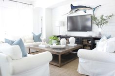 a living room filled with white furniture and a flat screen tv mounted to the wall