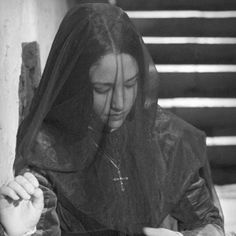 a woman in a nun outfit sitting on the ground with her hands clasped to her chest