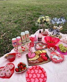 a table topped with lots of food on top of a lush green field covered in grass