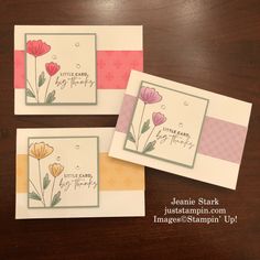 three cards with flowers on them sitting on top of a wooden table next to each other