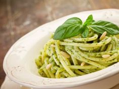 pasta with pesto and pine nuts in a white bowl