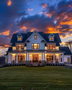 a large white house sitting on top of a lush green field under a cloudy sky