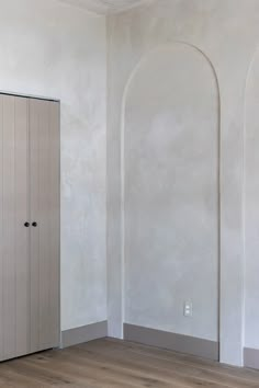 an empty room with white walls and wood flooring is pictured in this image, there are two doors on each side of the wall