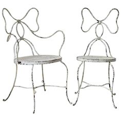 two white metal chairs with bows on them