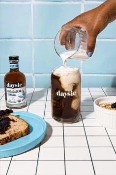 a person pouring something into a glass on top of a plate next to some food