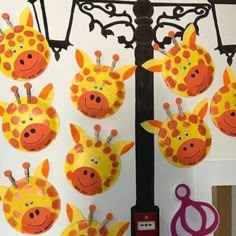 some paper plates with giraffes on them hanging from a light pole in front of a wall