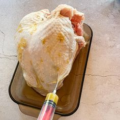 a large piece of meat on a tray with a syringe