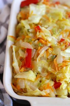 a casserole dish with cabbage, carrots and peppers in it on a table cloth