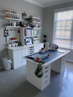 a sewing machine sitting on top of a white desk in a room with lots of shelves