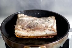 a piece of meat cooking in a frying pan on the stove top with some oil