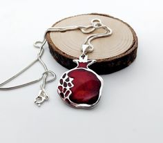 Add a touch of elegance and meaning to your jewelry collection with this handcrafted cloisonné enamel pomegranate pendant, designed and made with love. The vibrant red tones symbolize abundance, prosperity, and life, making this piece not only a stunning accessory but also a thoughtful gift for someone special. This pendant is crafted on fine silver using the traditional  Georgian cloisonne enamel technique, giving it a rich, glossy finish that ensures durability and timeless beauty. It hangs gracefully on a sterling silver chain, perfect for casual wear or special occasions.  Cloisonne enamel is one of the most valuable achievements of Georgia's diverse culture, it has a centuries-old history. Cloisonne enamel is the art of metal and glass merging and its manufacturing process is quite la Pomegranate Pendant, Cloisonne Enamel Jewelry, Pomegranate Jewelry, Cloisonne Enamel, Enamel Jewelry, Manufacturing Process, Fine Silver, Artisan Jewelry, Sterling Silver Chain