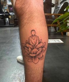 a man's leg with a tattoo on it that has a buddha sitting on top of a lotus flower