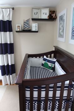 a baby's crib in the corner of a room with pictures on the wall