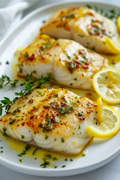 two fish fillets on a white plate with lemons and parsley garnish