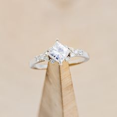 a diamond ring sitting on top of a wooden stand