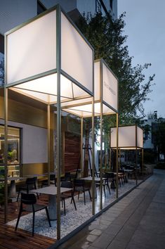 an outdoor dining area with tables and chairs on the side of it at night time