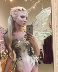 a woman dressed as a fairy holding a cell phone