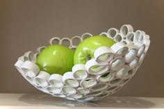 two green apples are in a white bowl