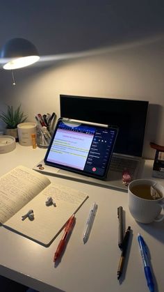 an open laptop computer sitting on top of a desk next to a cup of coffee