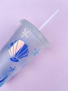 a plastic cup with a straw in it on a purple surface, next to a starfish design