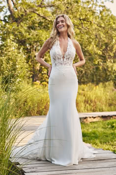 a woman in a wedding dress standing on a wooden platform with her hands on her hips