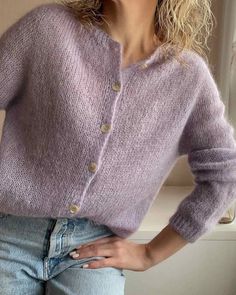 a woman is wearing a purple sweater and jeans