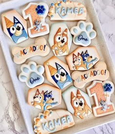 decorated cookies in the shape of dogs and cats on a tray with name tags for each dog